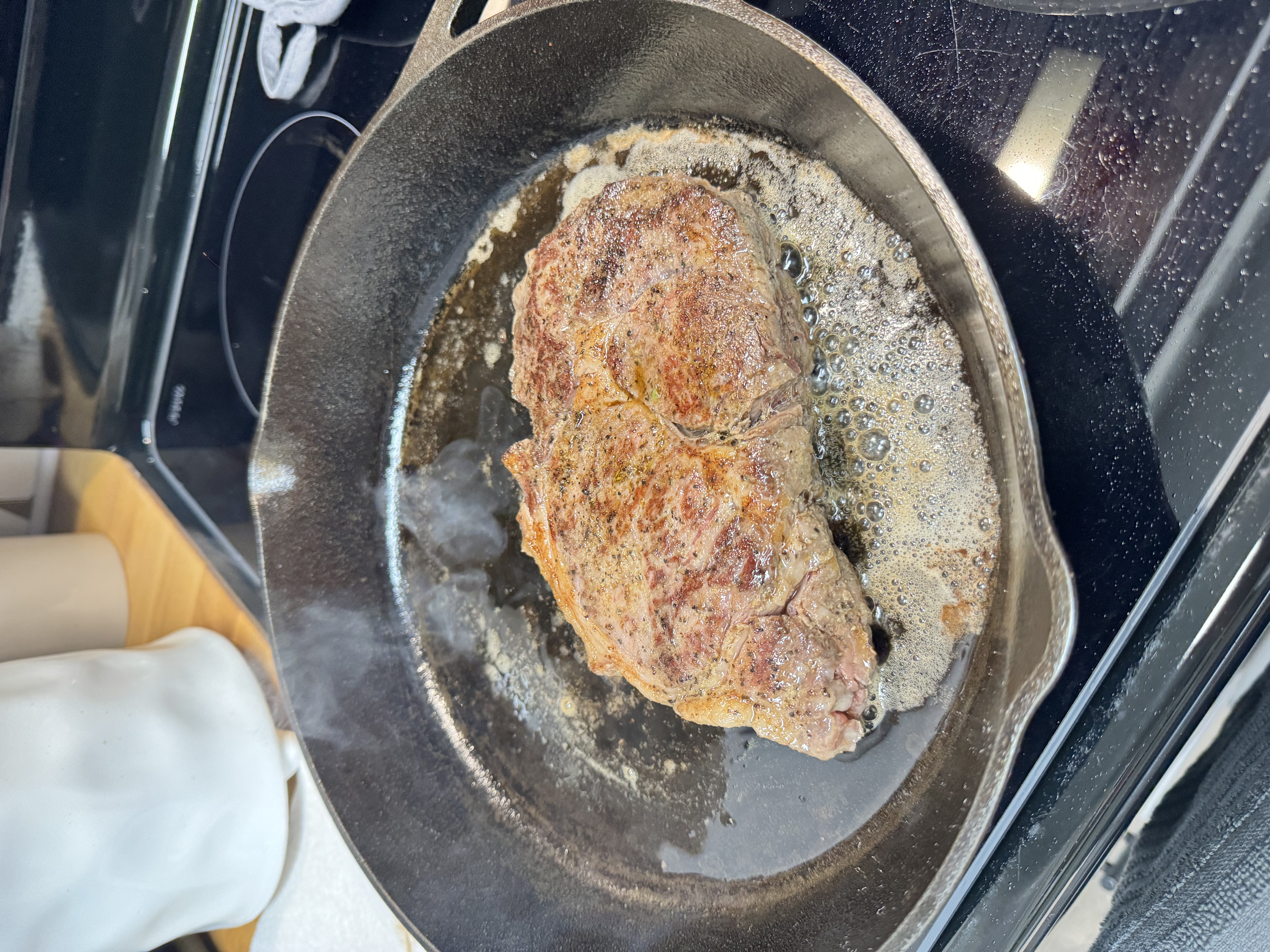 Steak being seared in cast iron pan.